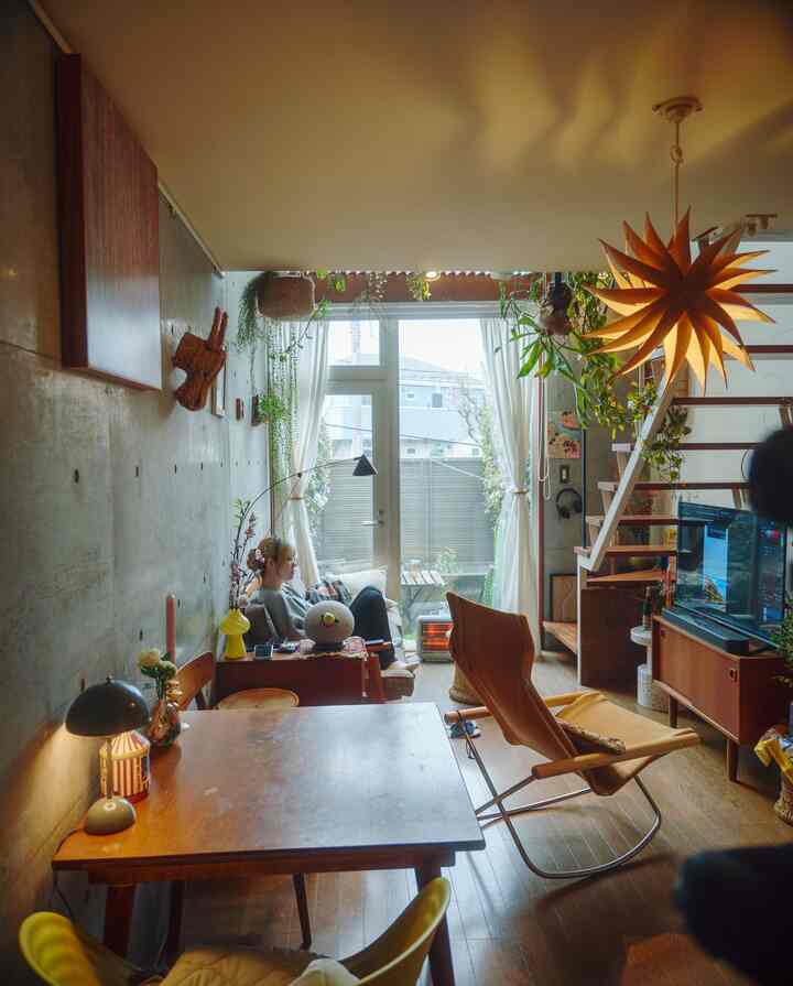 ナチュラルなブラウン調の縦長リビングとダイニング、階段とペンダントライトが配置された落ち着いたインテリア