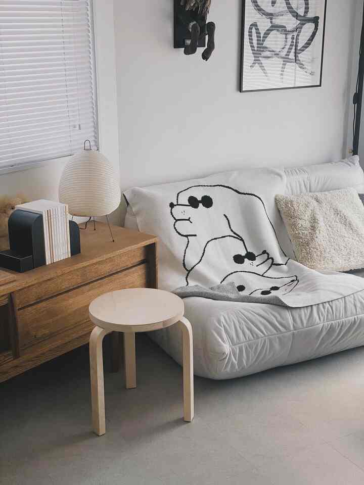 White and wood tone living room featuring a cozy sofa, sideboard, and floor lamp with a warm atmosphere