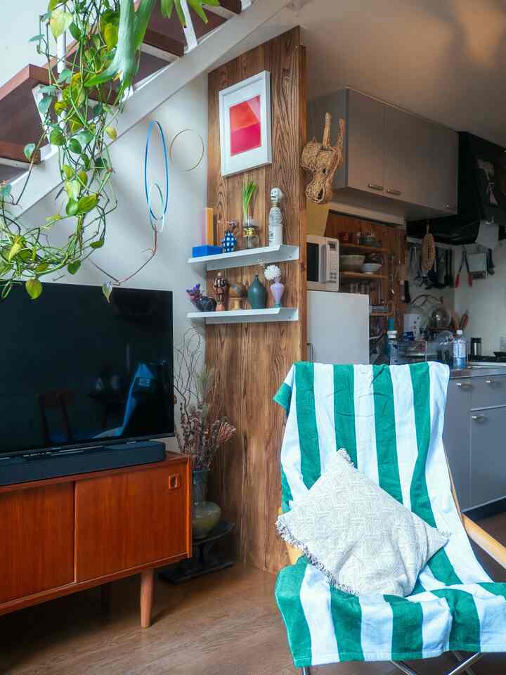 ナチュラルな木目調の二人暮らしリビング、DIYの壁パネルとアームチェア、テレビ台が配置された落ち着いた雰囲気のインテリア