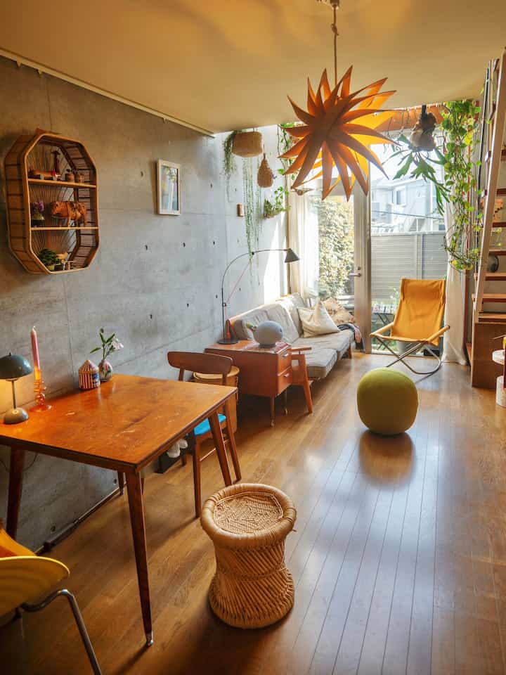 Warm brown wood-tone long and narrow living room for two, featuring a yellow armchair and wooden dining table with natural decorations