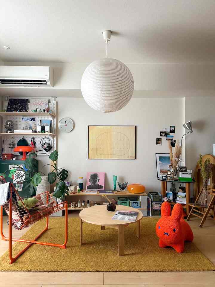 黄色とオレンジの色調のリビング、ナチュラルウッドのコーヒーテーブルと多彩な装飾が配された雰囲気のある空間