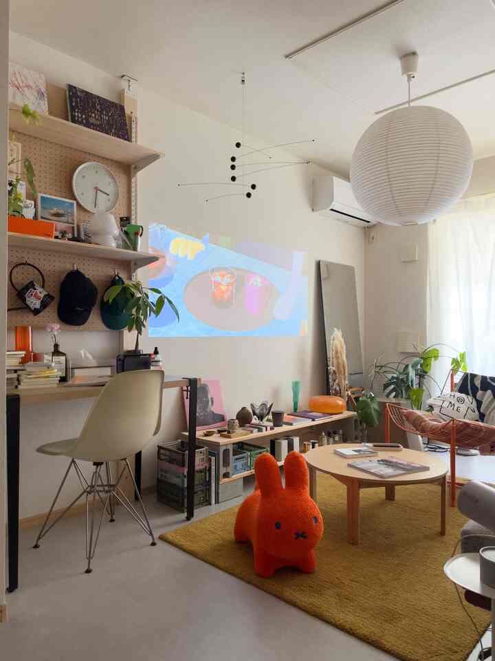 黄色いラグとミッドセンチュリーモダン家具が配置された自然な雰囲気のホームオフィスを兼ねたリビング