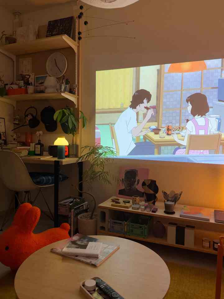 暖かみのある木目調のコンパクトなリビング、壁に映像が投影されたホームシネマの印象的な空間