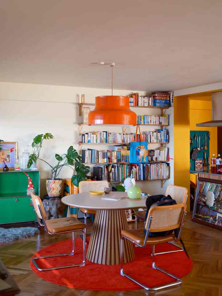 オレンジと赤のアクセントがあるダイニングルーム、中サイズの木製ダイニングテーブルとモダンな椅子が配置された温かみのある雰囲気の空間