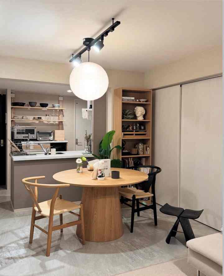 白と木目調の調和が美しい2LDKダイニング、丸い木製のダイニングテーブルと2脚の椅子、ペンダントライトが配置された印象的な空間