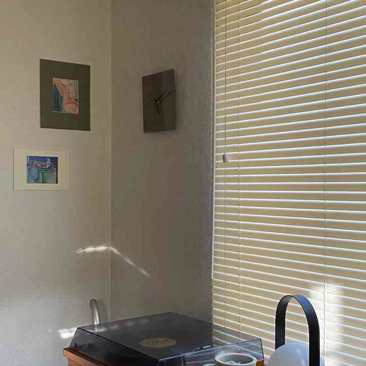 A cozy corner in a studio apartment featuring beige and silver tones, stainless steel clock, and record player