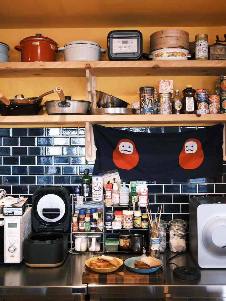 ナチュラルな色調のキッチン、木製棚とブルーのタイル壁が配置された雰囲気のあるインテリア