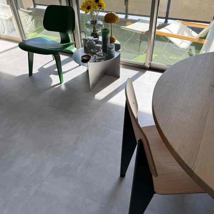 白を基調とした背景に木目調のダイニングテーブル、ミッドセンチュリーモダンな椅子、黄色のテーブルランプが置かれた明るいリビング空間