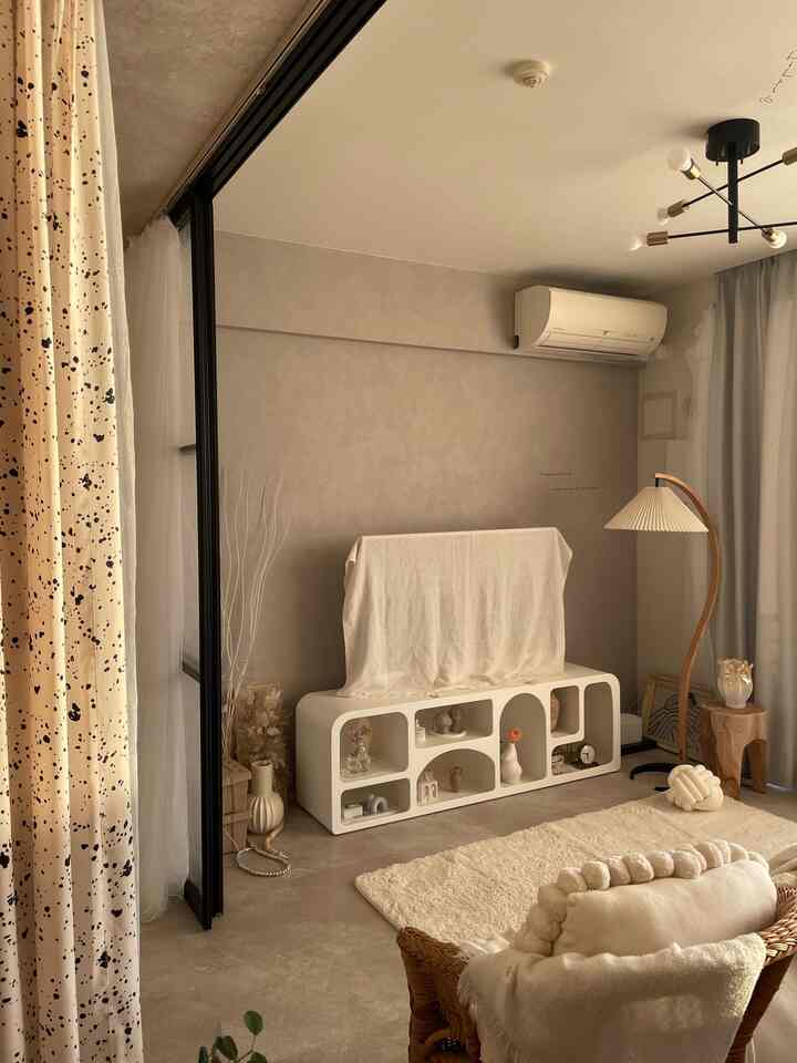 柔らかなベージュと白の色調のリビング、曲線的なテレビ台とフロアランプが調和したナチュラルモダンなインテリア