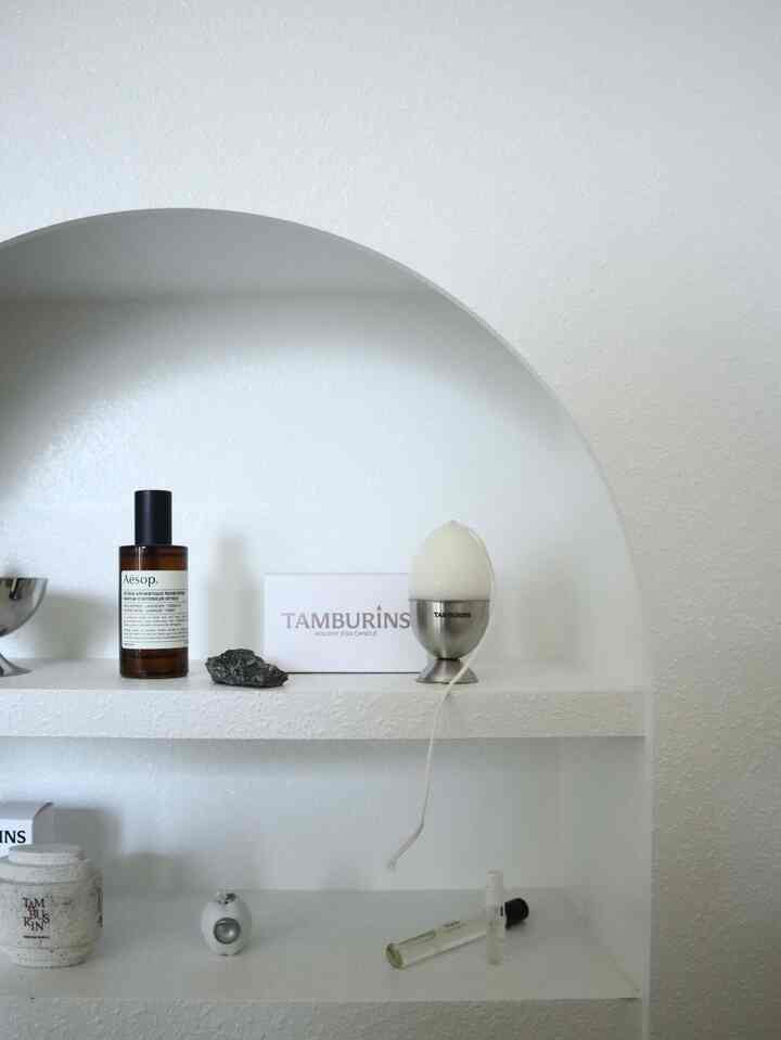 White-toned living room wall featuring a curved mantlepiece niche displaying simple decorative objects with a clean aesthetic