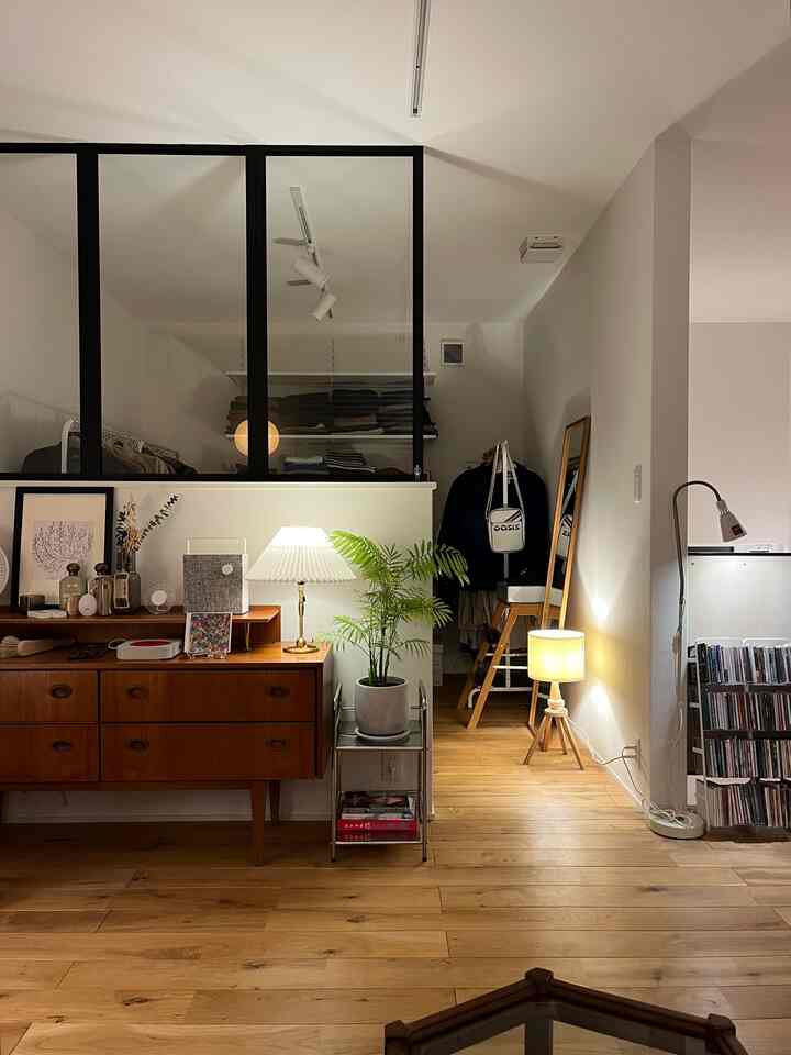 A walk-in closet space with wood tone flooring and vintage Mid-Century Modern furniture illuminated by soft indirect lighting