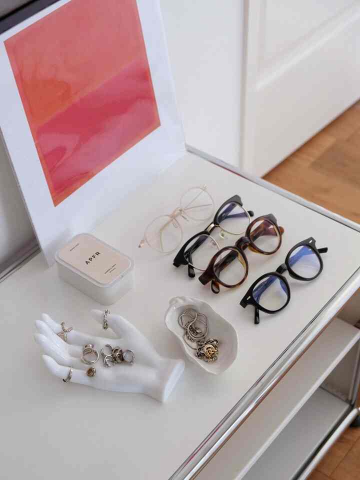 White-toned living room TV board surface featuring eyeglasses and jewelry accessories in a clean natural interior setting