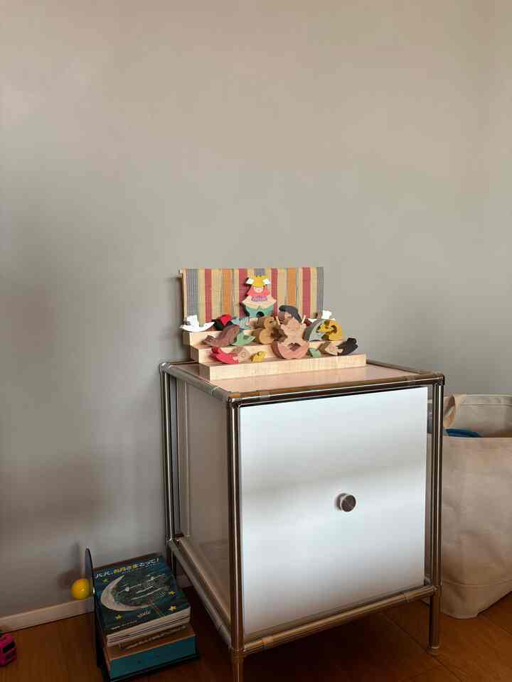 ナチュラルトーンの壁とホワイトのキャビネットが配置され、上に木製の五月人形が飾られた印象的な空間