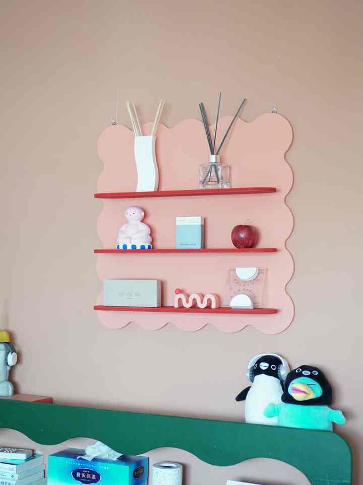 ピンク色の壁と棚がある寝室、グリーンのベッドヘッドボードとかわいい小物が配置された雰囲気のあるインテリア