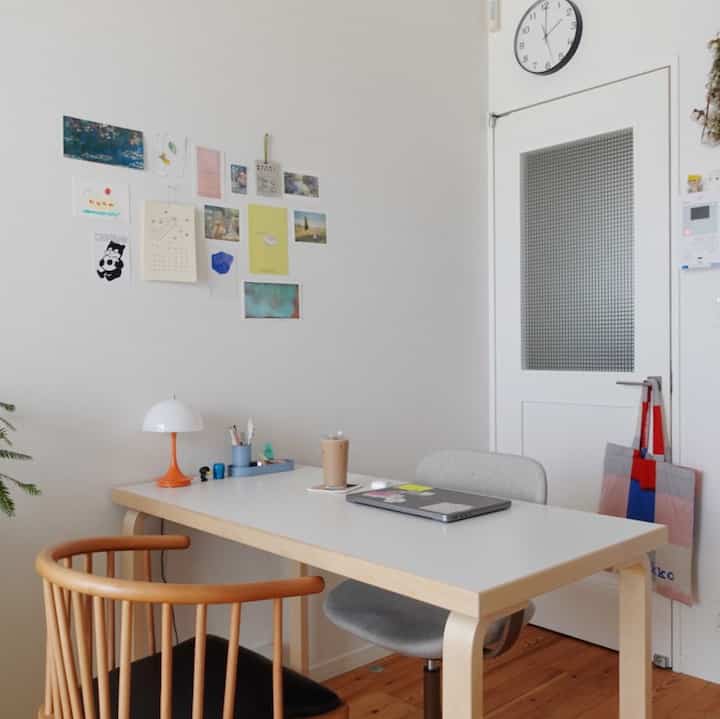 白い壁とナチュラルカラーの家具が配された北欧風のワンルーム、ホームオフィスとダイニングが融合した空間