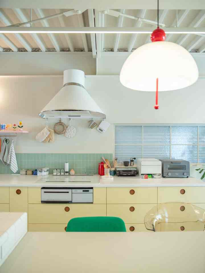 Modern kitchen in white and beige tones featuring green and transparent chairs with a natural and clean atmosphere