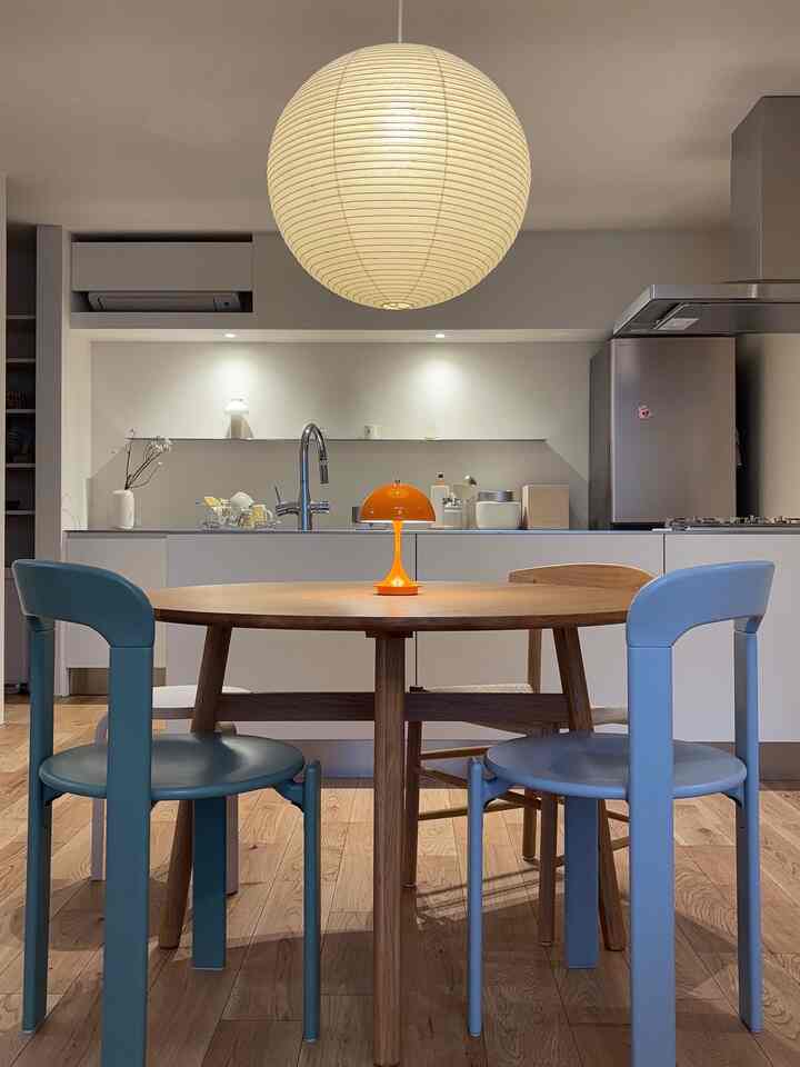 Modern dining room in white and wood tones, featuring a round dining table with navy dining chairs