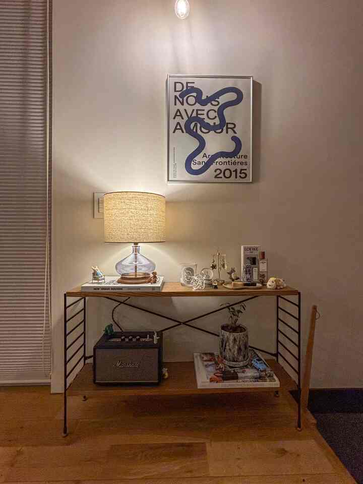 暖かい照明のナチュラルトーンのリビング、木製テーブルにはマーシャルスピーカーと額装されたアートが配置された雰囲気のあるインテリア