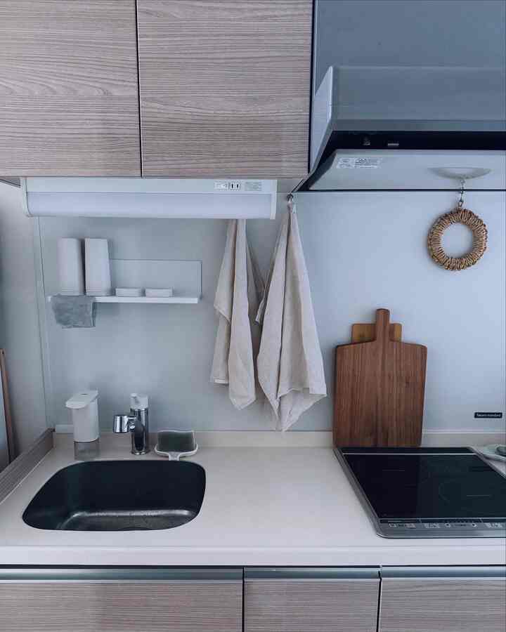 ホワイトと木目調が調和したキッチン、シンプルでミニマルなデザインのタオルとまな板が配置された印象的な空間