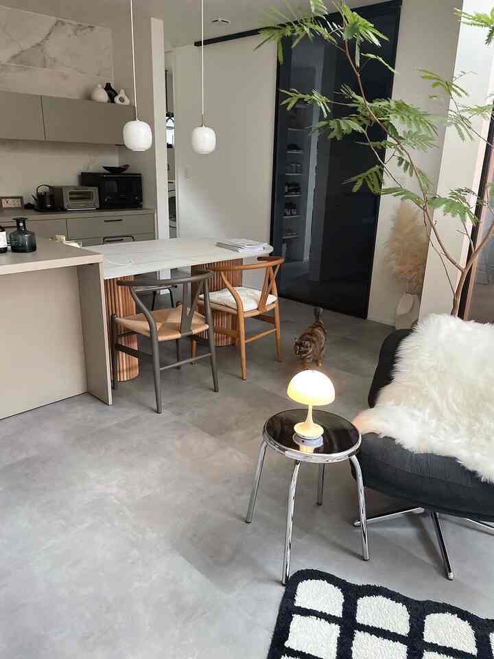 Gray and white toned dining and living room featuring wooden dining chairs and indoor plant, creating a minimal and natural atmosphere