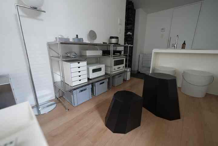 White and wood-tone kitchen space featuring sleek steel shelving and black stools in a minimalist interior