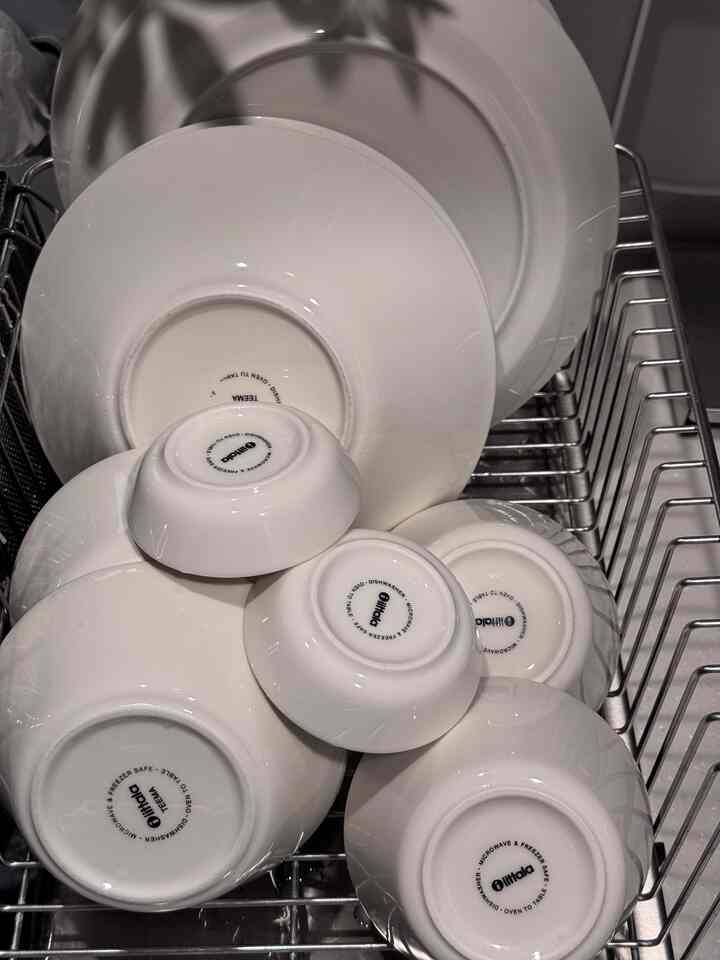 白を基調としたキッチンに、イッタラ ティーマシリーズの皿とボウルが食器棚に整然と並んでいる印象的な空間