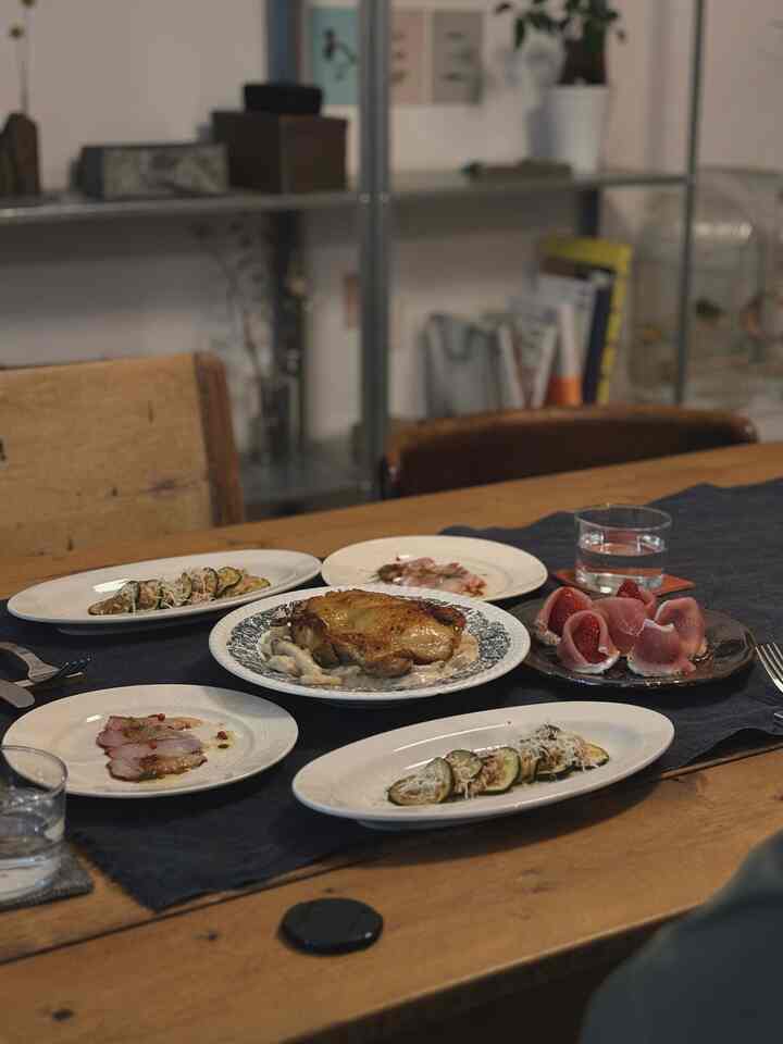 ナチュラルな木目調のダイニングテーブルに多彩な料理が並ぶ二人暮らしの印象的なダイニング空間