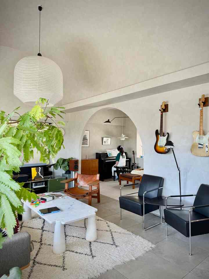 Natural-toned living room featuring an arched wall with a piano and child, creating a warm and cozy atmosphere