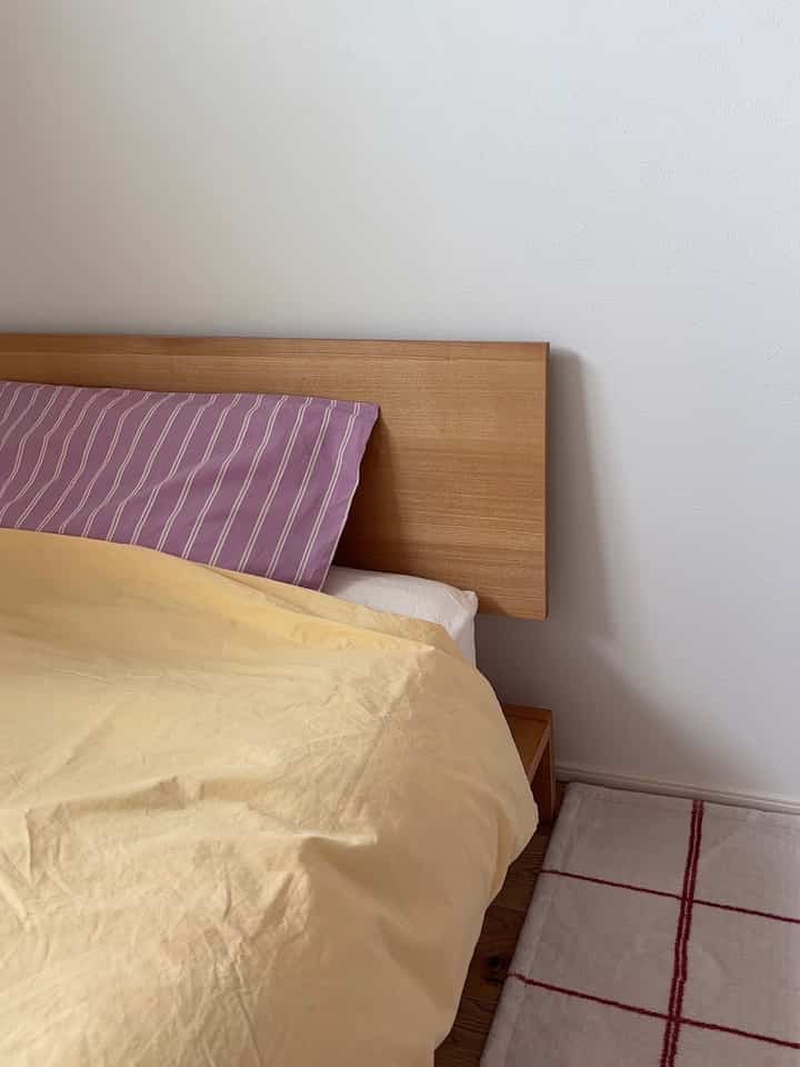 黄色の寝具と木目調のベッドが置かれた、清潔感のある子供部屋の一角とベッドの様子