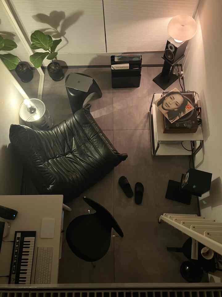 ブラックとグレーのトーンで構成された狭い一人暮らしの空間、レトロなレコードプレーヤーとソファが調和した雰囲気のあるインテリア