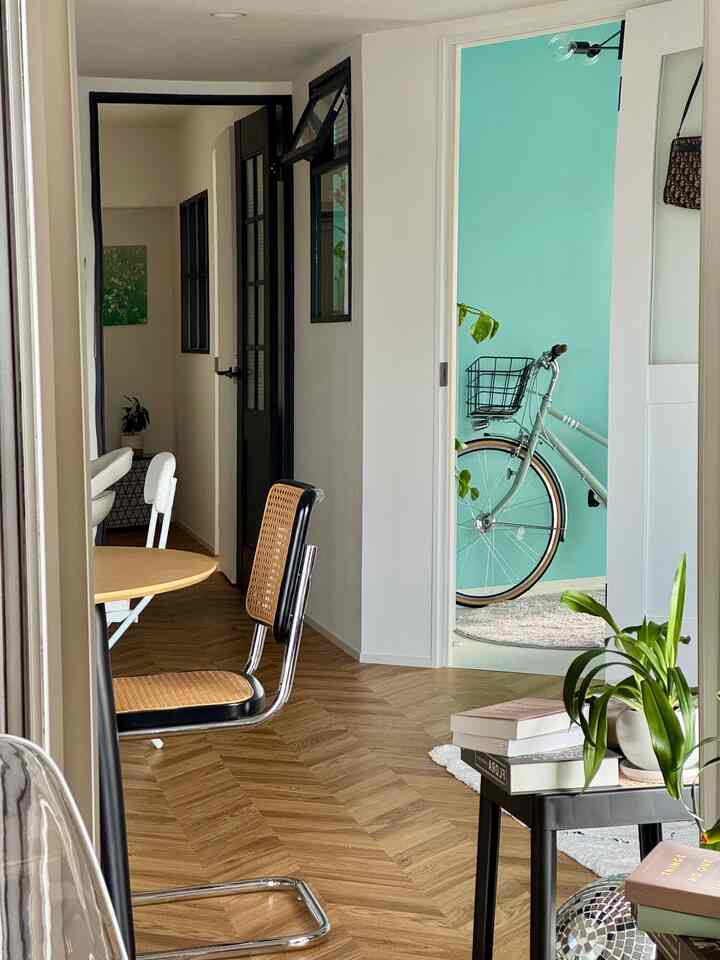 ナチュラルな木目調の床と白い壁が調和する二人暮らし向けのリビング・ダイニングルーム、バルコニーのそばに自転車が見える落ち着いた空間
