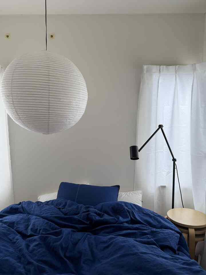Simple, modern bedroom with blue bedding and white walls and curtains