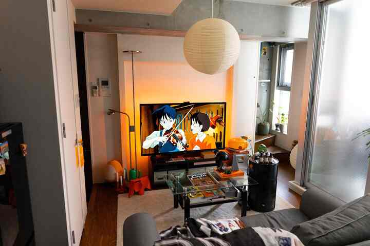 Nordic-style living room with gray sofa, glass coffee table, white pendant light, and warm ambient lighting