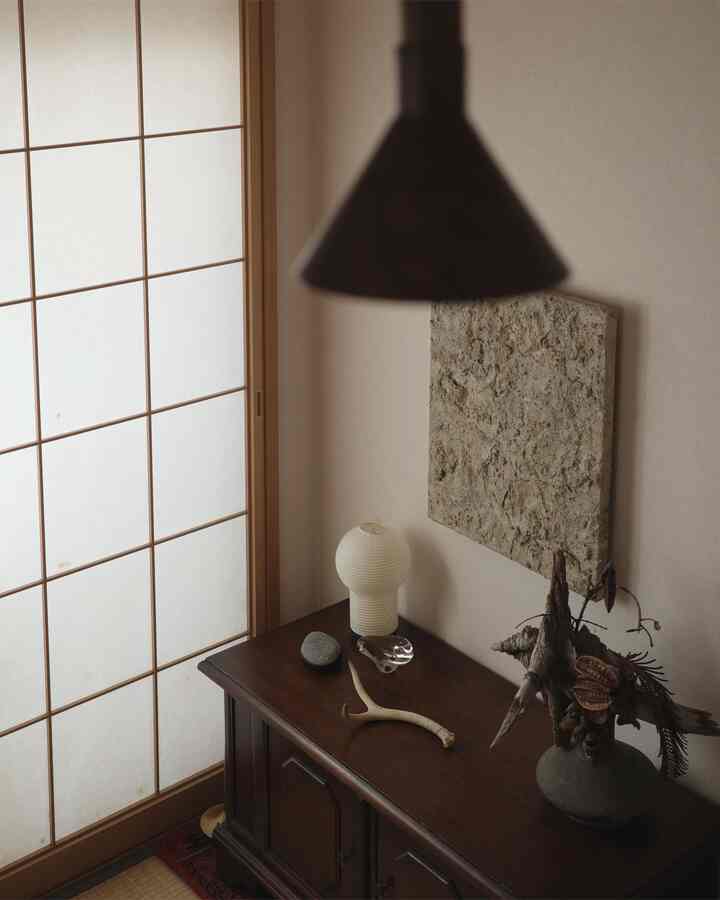 Beige and brown toned traditional corner featuring wooden cabinet with light and plant decor for a natural interior