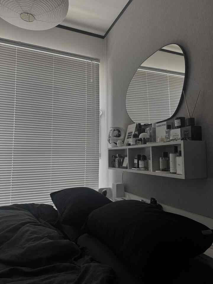 Gray-toned bedroom featuring aluminum blinds and black bedding, presenting a modern cozy atmosphere