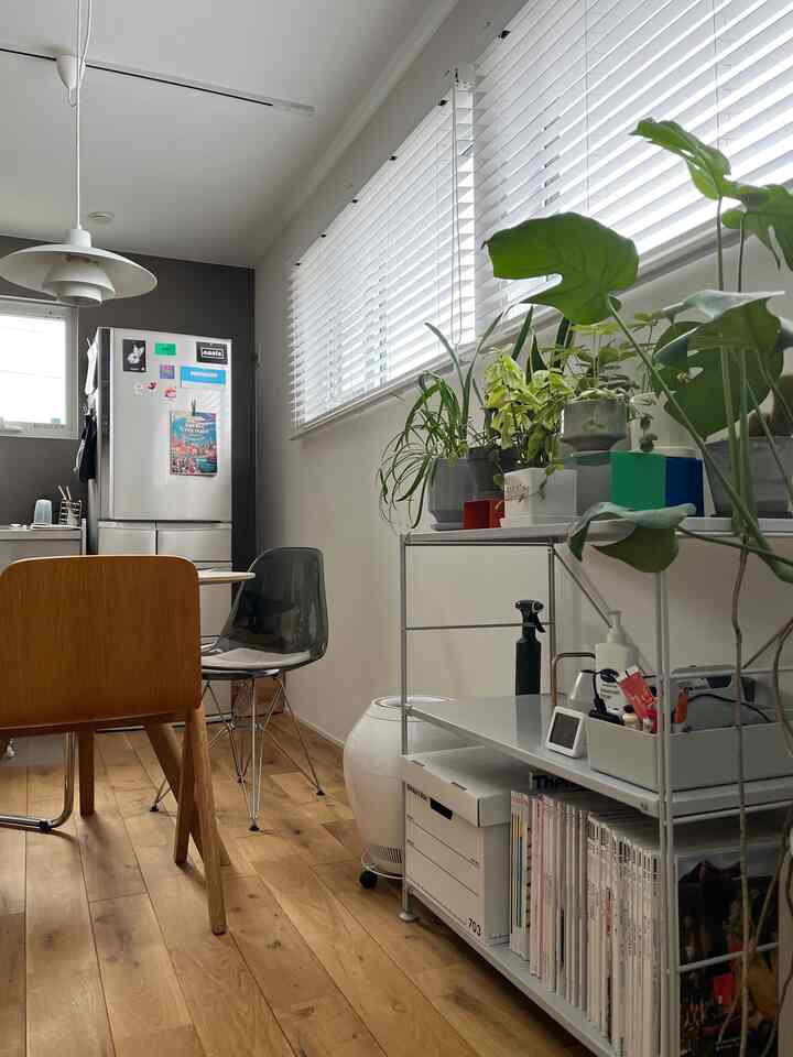 White and natural color dining room featuring wooden dining table, chairs, and green plants with neat atmosphere