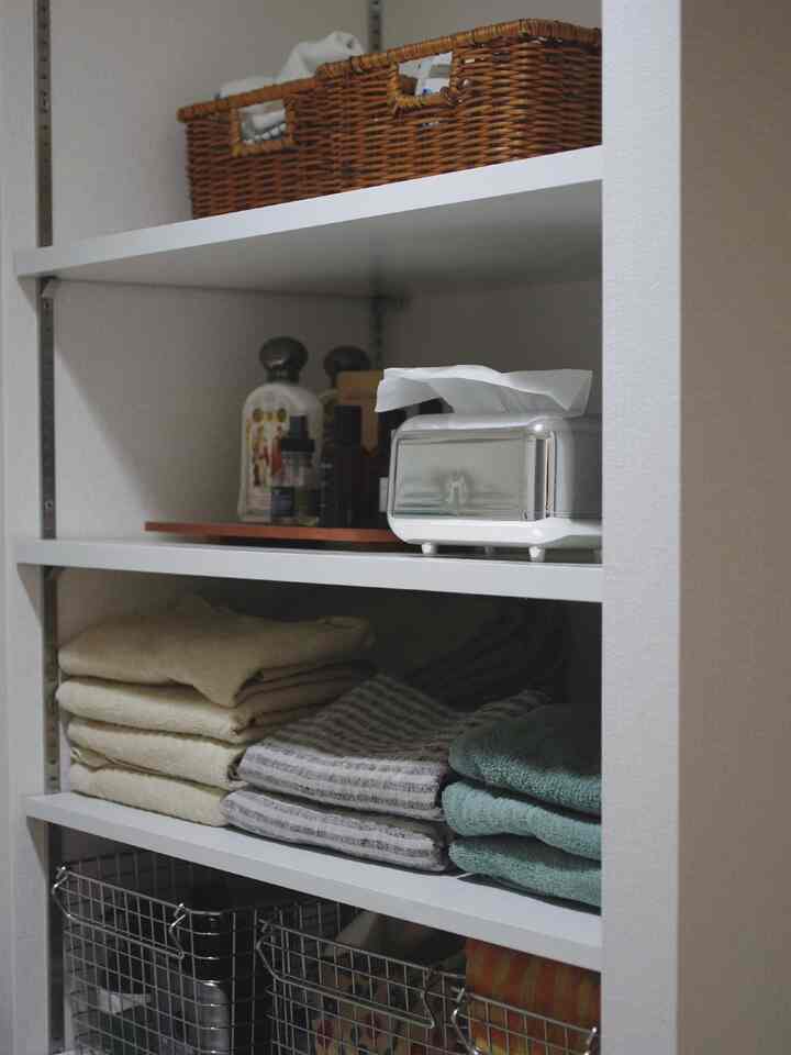 White shelving storage space with brown baskets and neatly folded towels, a practical and organized area