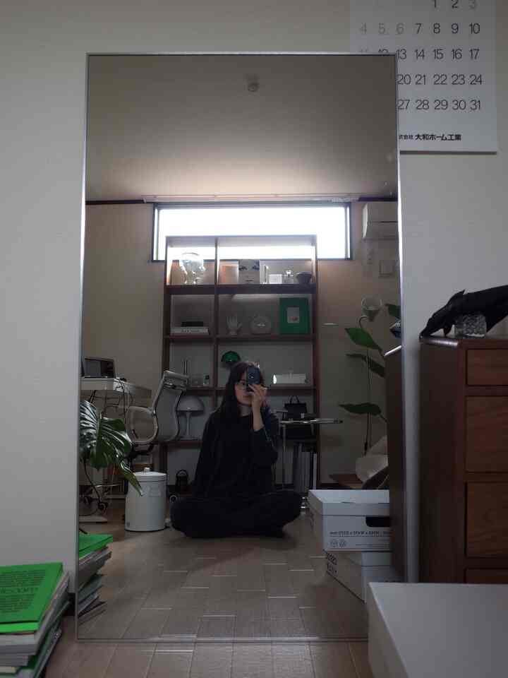 Natural tone study featuring a large full-length mirror with a single person sitting in front, cozy and minimalist