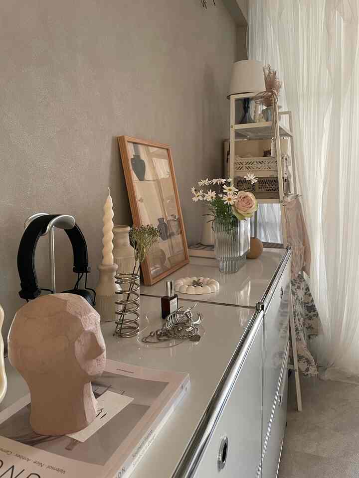 ナチュラルな色調の子供部屋、白い収納棚と飾り棚に花瓶やランプが配置された印象的な空間