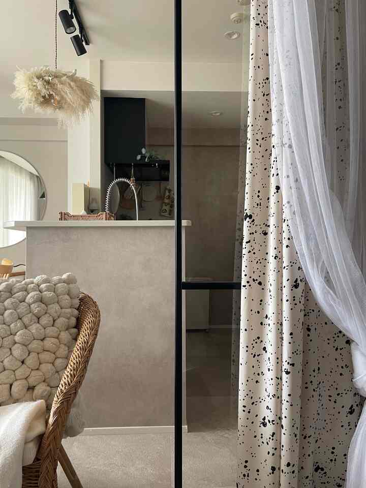 Beige-toned compact kitchen space featuring layered curtains and a rattan armchair with a natural atmosphere