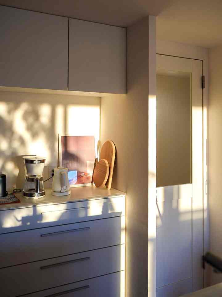 Warm white and natural tone kitchen featuring a coffee maker and electric kettle in a simple cozy home cafe space
