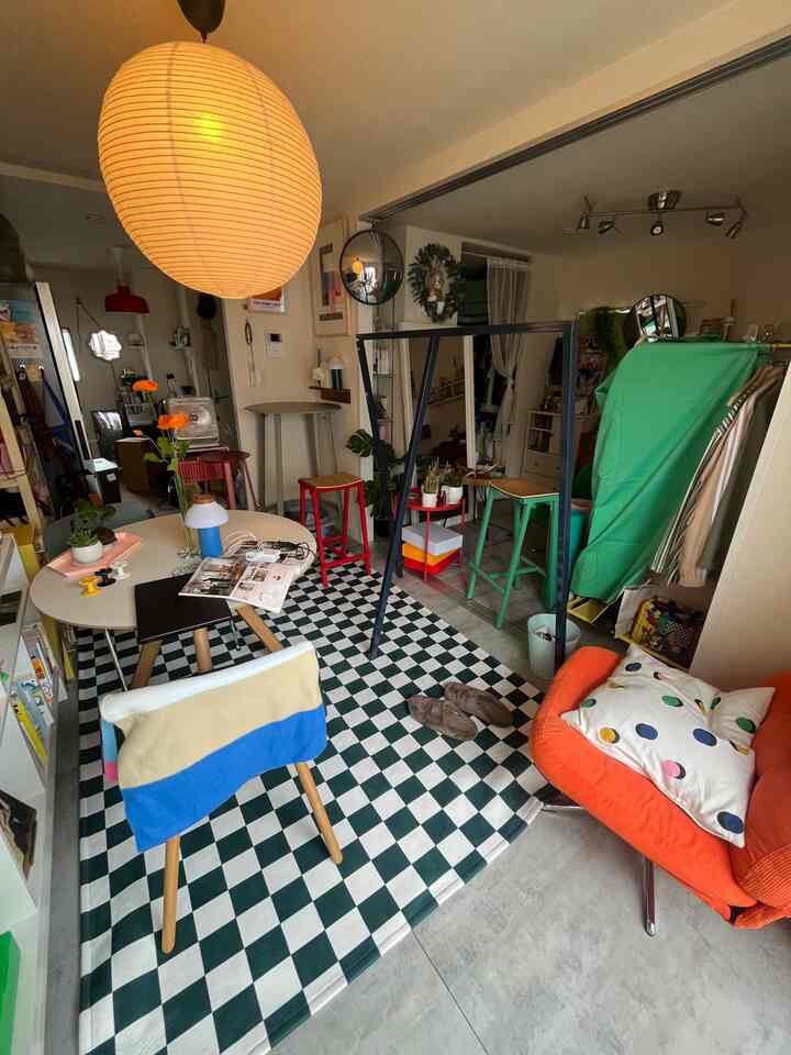 A cozy cafe-style kitchen space in white and orange tones featuring a checkerboard rug and Mid-Century Modern furniture