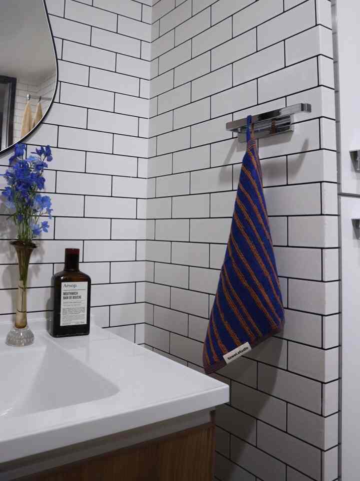 Modern bathroom sink area with white tiled walls and a blue towel