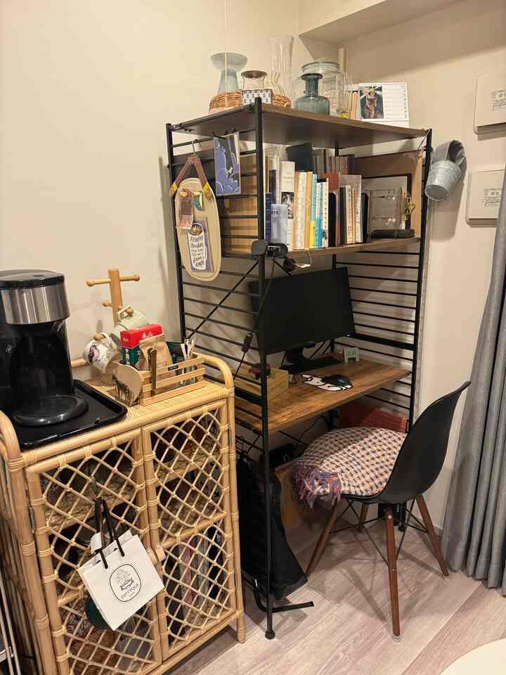 ウッドトーンとブラックが調和するコンパクトなホームオフィスのワークスペース。籐製キャビネットと棚上の花瓶が配置された落ち着いた空間