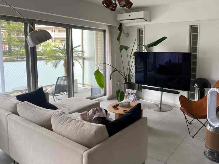 A white and wood-toned living room for four, featuring mid-century modern sofa and plants creating a cozy atmosphere