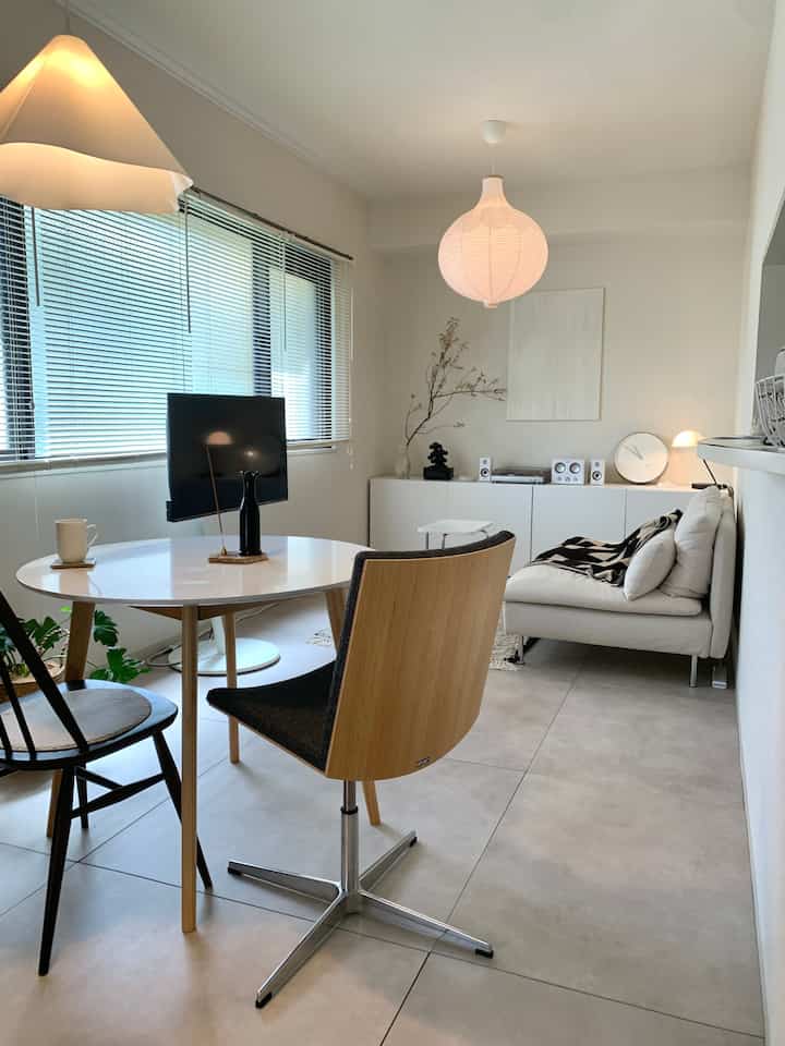 Bright living room with white and natural tones featuring a large onion-shaped pendant light and round dining table, simple and airy atmosphere