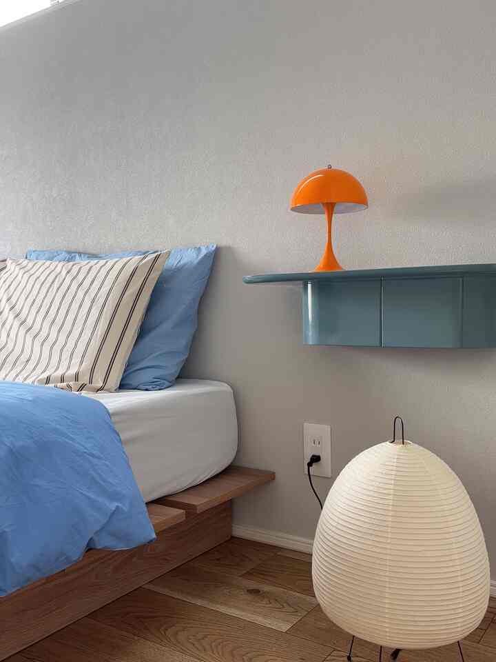 Natural wood tone and blue bedroom featuring an orange table lamp and clean modern style interior