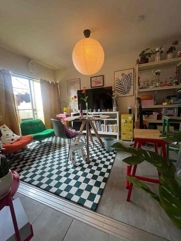 ナチュラルな色調のリビング、中央にチェッカーボードラグとカラフルなアームチェアが配置された雰囲気ある空間