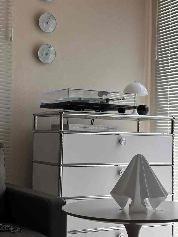 アイボリー色の壁とクローム家具が調和したモノトーンのリビング、オーディオ機器が収納されたシンプルな空間