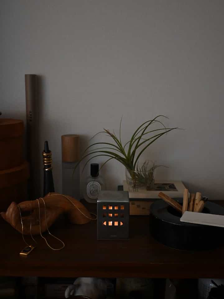 Dark wood tabletop featuring a candle holder, plant, and incense sticks, creating an elegant decorative setting